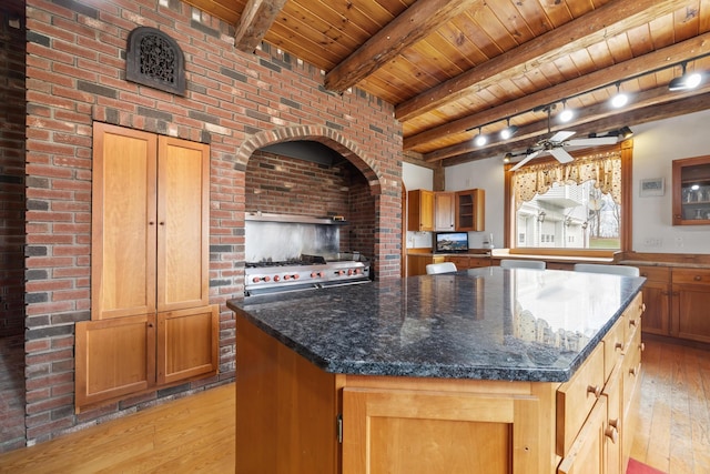kitchen with wood ceiling, a ceiling fan, a kitchen island, beam ceiling, and light wood finished floors