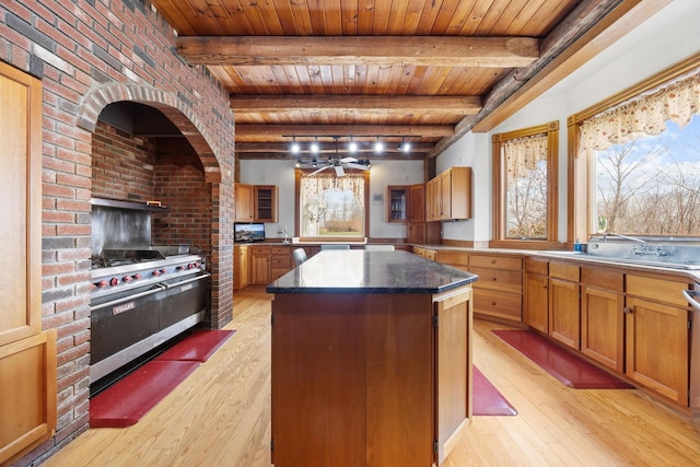 kitchen with ceiling fan, range with two ovens, light wood-type flooring, a kitchen island, and wood ceiling