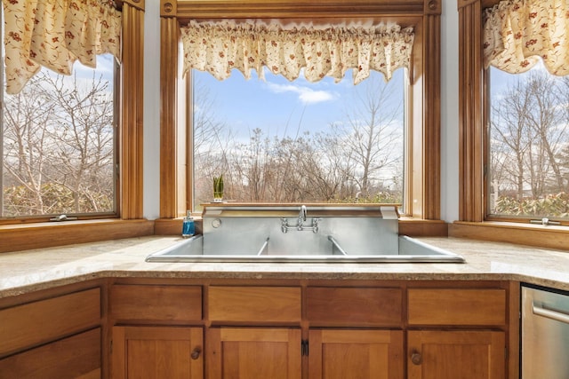 interior space with a sink, brown cabinetry, and dishwasher