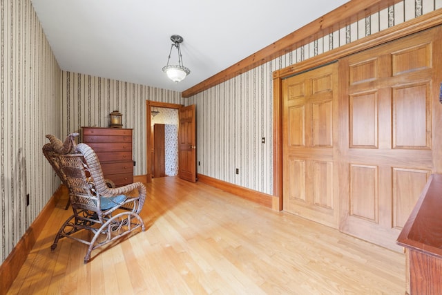 sitting room featuring baseboards, wood finished floors, and wallpapered walls