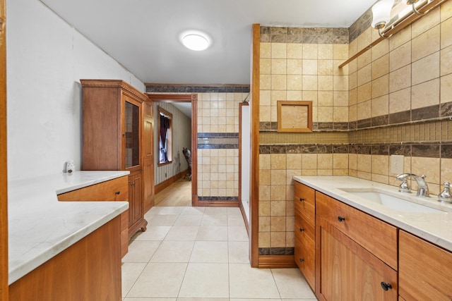 full bath featuring tile walls, tile patterned flooring, vanity, and a shower