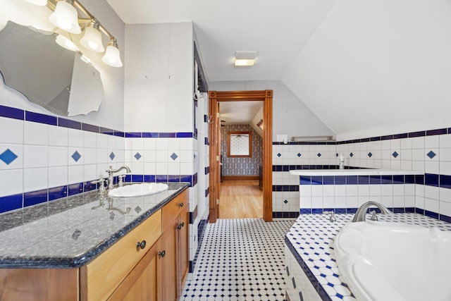full bathroom featuring a bath, tile walls, vaulted ceiling, vanity, and tile patterned floors