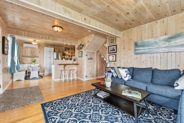 living room with wooden ceiling, light wood-style floors, wood walls, an AC wall unit, and stairway