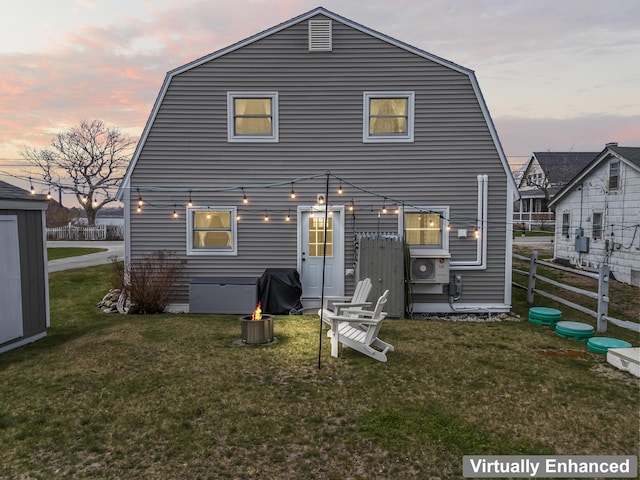 back of property at dusk with fence, a gambrel roof, and a yard