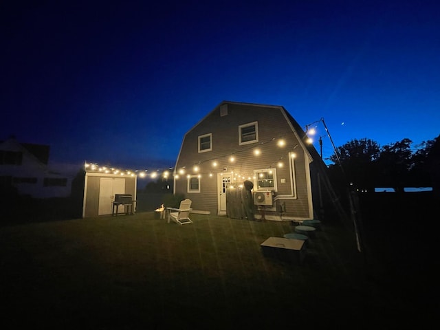 back of house at night featuring a gambrel roof