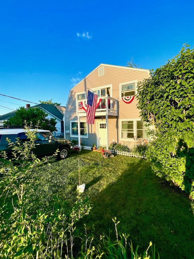 view of front of house with a front lawn and a balcony