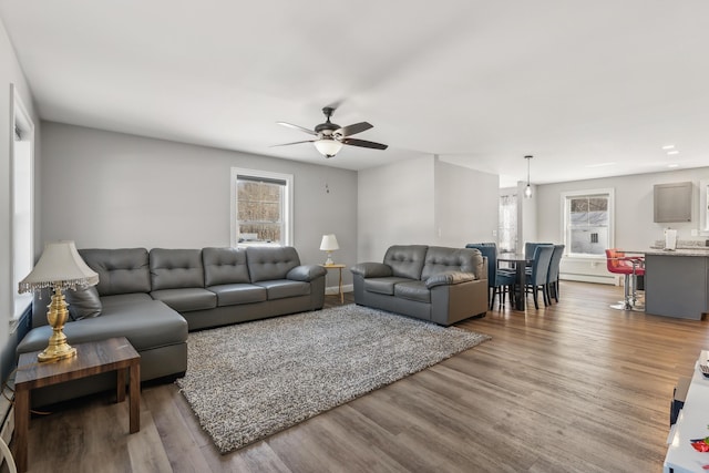 living room with a ceiling fan, a baseboard heating unit, and wood finished floors