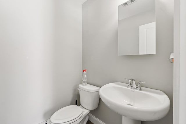 bathroom with a sink, toilet, and visible vents