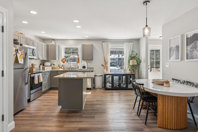 kitchen with a breakfast bar, a center island, a sink, a wealth of natural light, and stainless steel appliances
