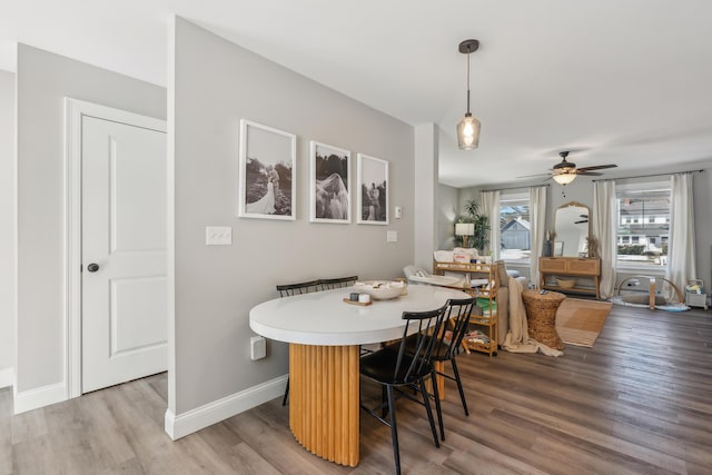 dining room with a ceiling fan, baseboards, and wood finished floors