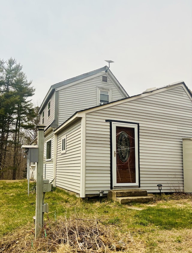 rear view of house featuring a lawn and entry steps