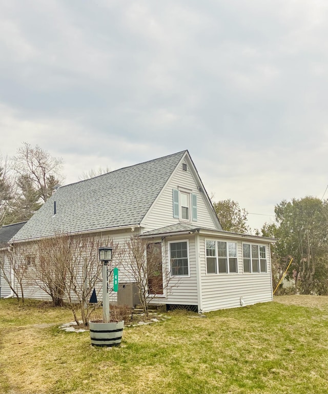 rear view of property with a lawn, roof with shingles, and central air condition unit