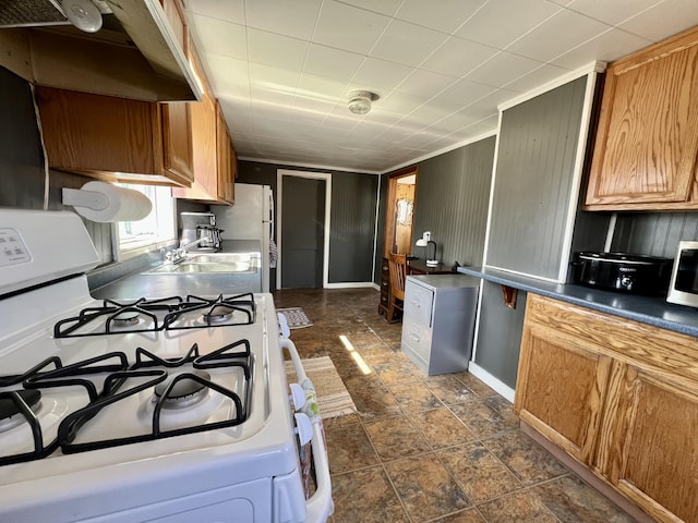 6 Lyons St, Machias, ME 04654 - kitchen with under cabinet range hood, brown cabinetry, white appliances, a sink, and dark countertops
