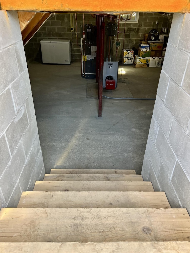 6 Lyons St, Machias, ME 04654 - stairs with concrete floors, water heater, and concrete block wall