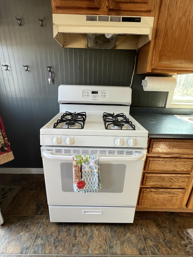 6 Lyons St, Machias, ME 04654 - kitchen featuring under cabinet range hood, gas range gas stove, brown cabinets, and dark countertops