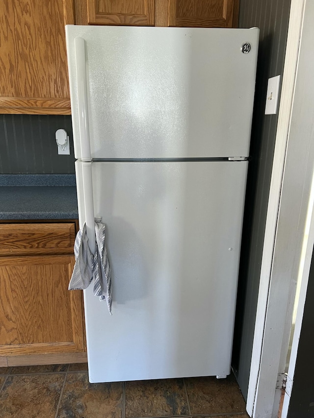 6 Lyons St, Machias, ME 04654 - kitchen with dark countertops, freestanding refrigerator, brown cabinetry, and stone finish floor