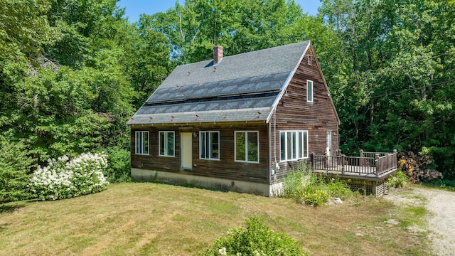 view of side of home featuring a lawn, a wooden deck, and a chimney