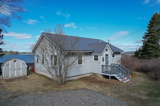 back of house featuring an outbuilding, a storage shed, a yard, and metal roof