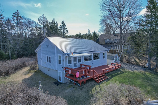 rear view of property featuring a lawn, a standing seam roof, metal roof, and a deck