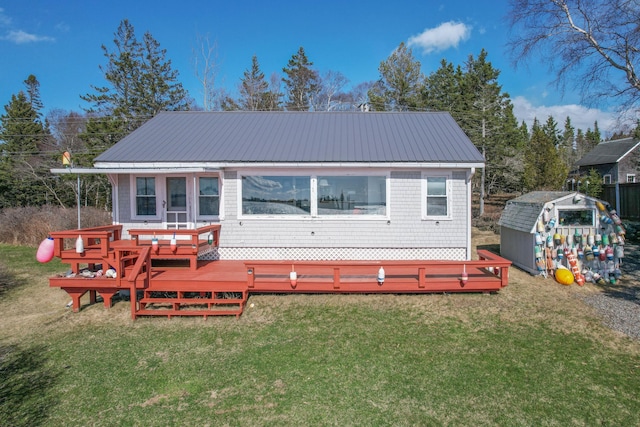 rear view of house with a deck, an outdoor structure, metal roof, and a lawn