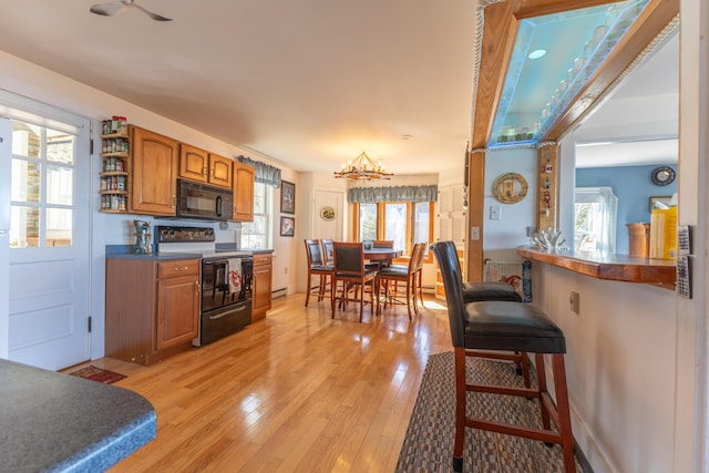 kitchen with black microwave, plenty of natural light, and range with electric stovetop
