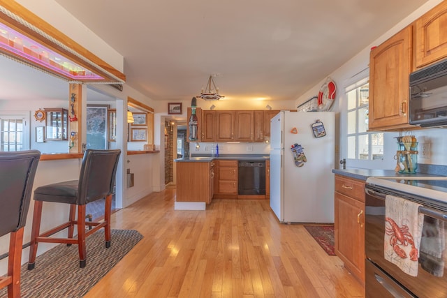 kitchen with black appliances, brown cabinets, light wood-type flooring, and plenty of natural light