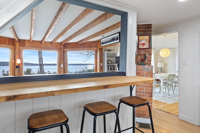 kitchen featuring a water view, a breakfast bar, butcher block counters, and light wood finished floors