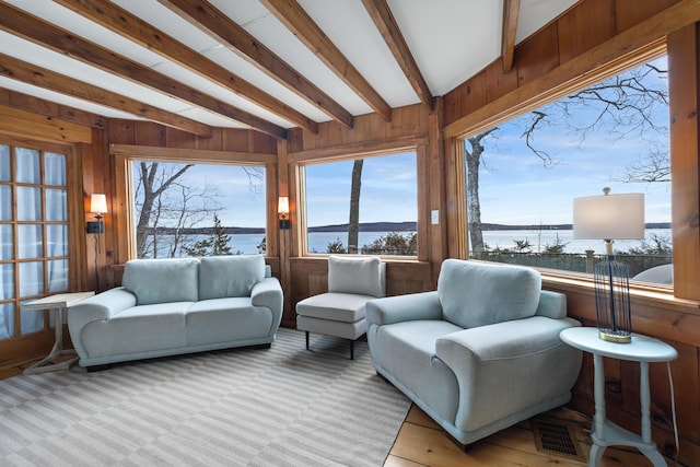living area with wood walls, a water view, and beam ceiling