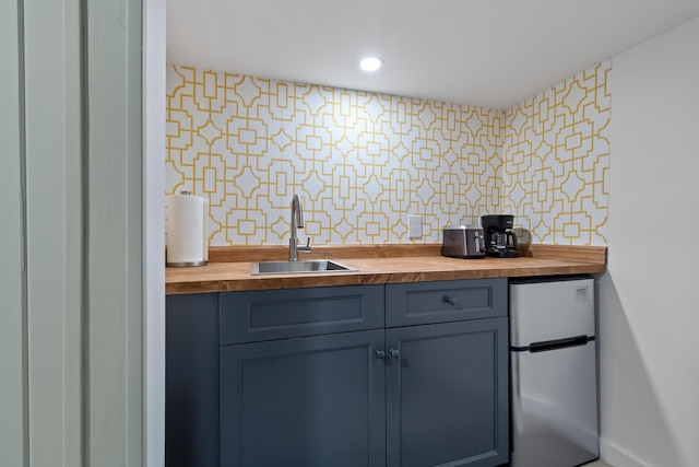 kitchen with tasteful backsplash, a sink, freestanding refrigerator, recessed lighting, and butcher block countertops