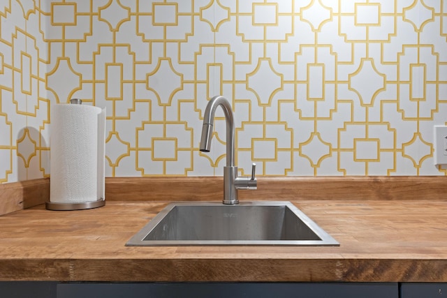 details featuring wood counters, wallpapered walls, and a sink