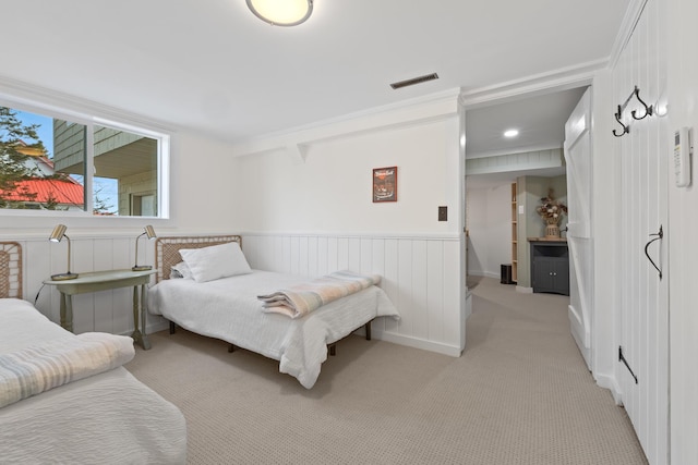 bedroom featuring wainscoting, visible vents, and light carpet