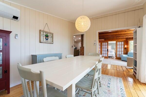 dining area with a wall unit AC and light wood-style flooring