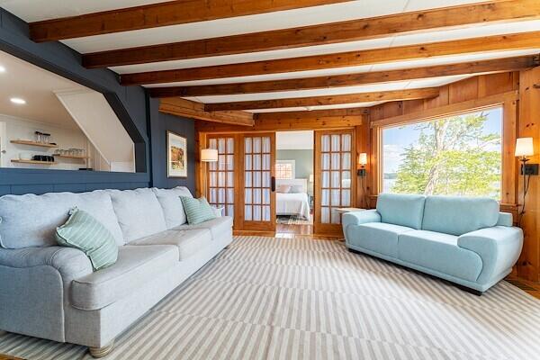 living room featuring wooden walls, recessed lighting, beam ceiling, and french doors