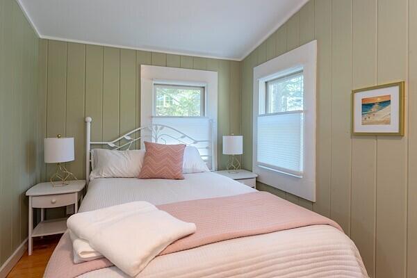 bedroom featuring multiple windows, wood finished floors, and a decorative wall