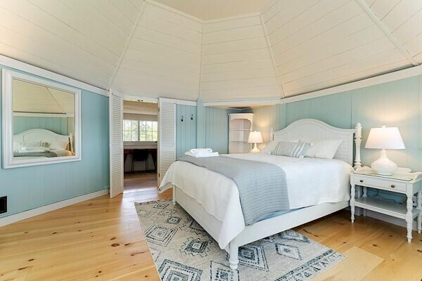 bedroom with baseboards, wood finished floors, and vaulted ceiling