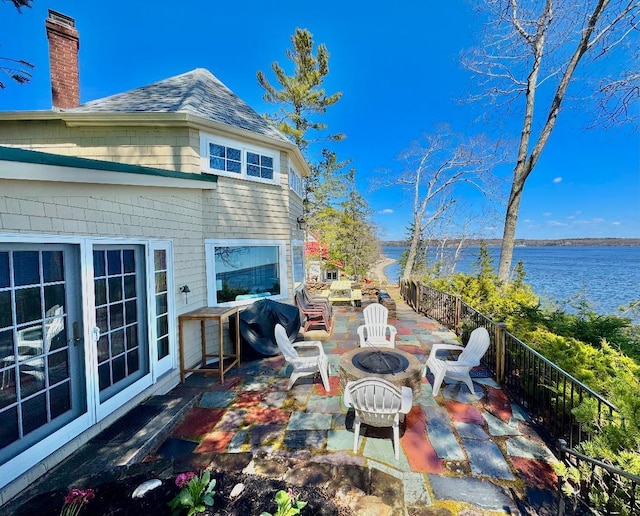 view of patio featuring fence, a water view, and a fire pit