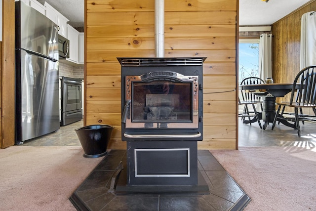 135 Williams Rd, Newport, ME 04953 - interior details with wooden walls, a wood stove, carpet flooring, and appliances with stainless steel finishes