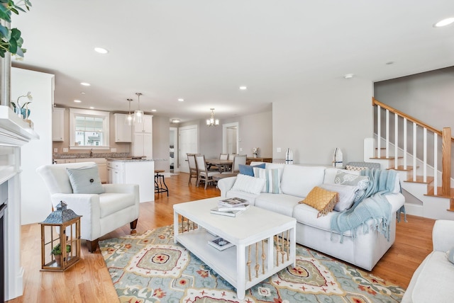 living area with recessed lighting, a fireplace, light wood-style floors, and stairway