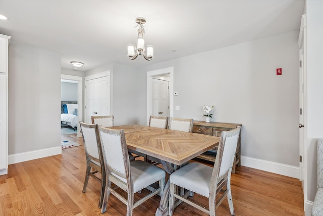 dining room featuring a chandelier, light wood-style floors, and baseboards