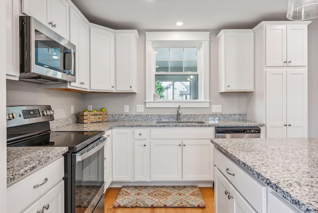 kitchen featuring a sink, white cabinets, appliances with stainless steel finishes, and light wood-style floors