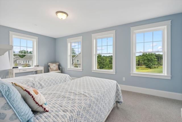 carpeted bedroom featuring baseboards and multiple windows