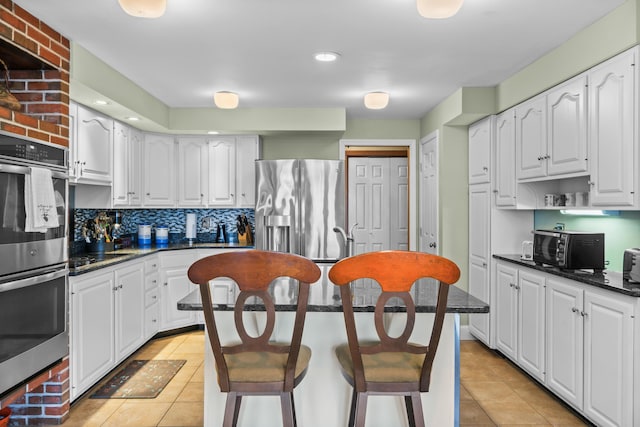 kitchen featuring light tile patterned floors, a kitchen island, appliances with stainless steel finishes, and white cabinetry