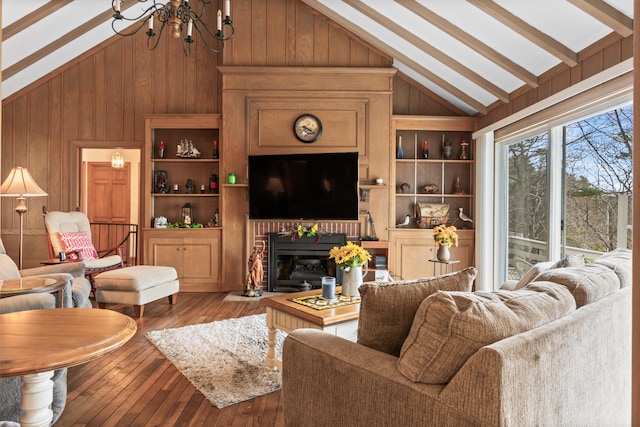 living area featuring a notable chandelier, hardwood / wood-style floors, wooden walls, built in features, and vaulted ceiling with beams