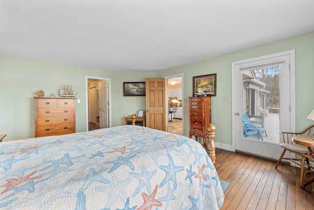 bedroom with baseboards, access to exterior, and wood-type flooring