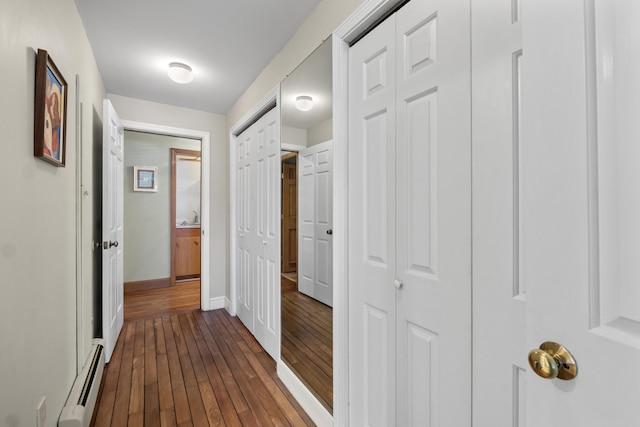 corridor with baseboards, a baseboard radiator, and dark wood-type flooring