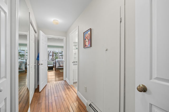 hall with a baseboard radiator, light wood-type flooring, and baseboards