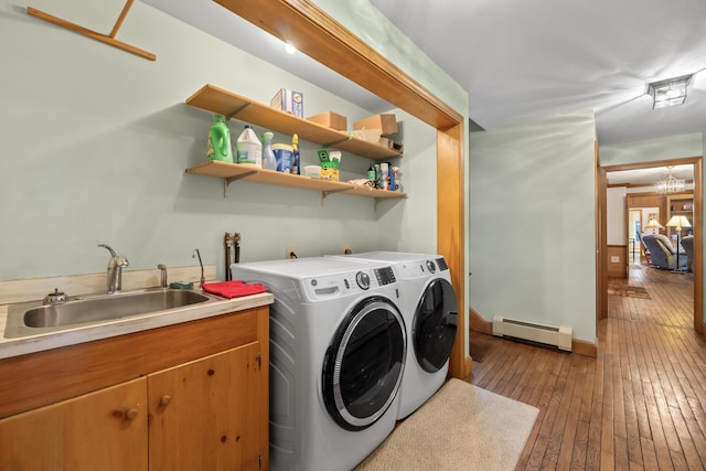 washroom with a sink, hardwood / wood-style floors, a baseboard heating unit, baseboards, and washer and dryer