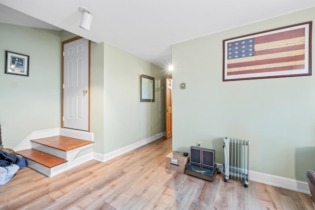 interior space with baseboards, radiator heating unit, and light wood finished floors