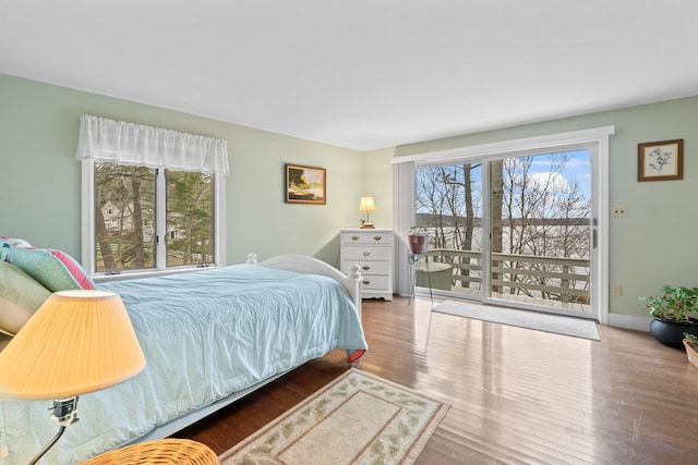 bedroom featuring wood finished floors, baseboards, and multiple windows