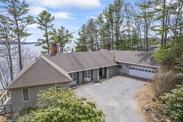 single story home featuring driveway, a chimney, a shingled roof, and a garage